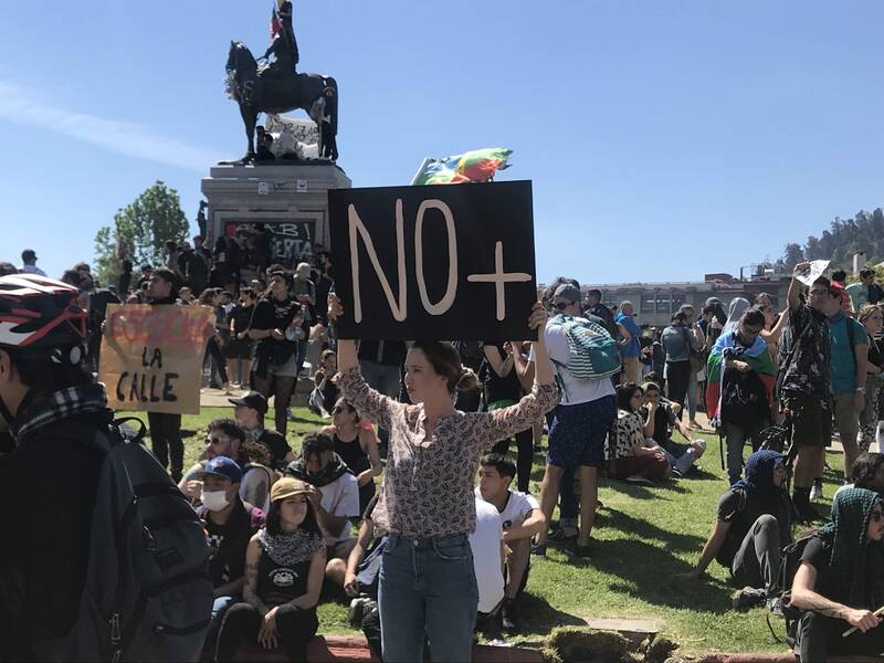 Personas reunidas en Plaza Dignidad y cartel "No más"